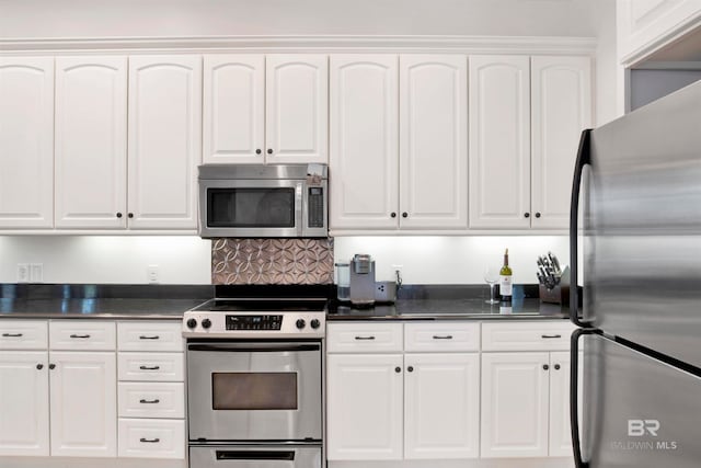 kitchen with appliances with stainless steel finishes, white cabinets, and tasteful backsplash