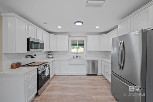 751 Abbey Way, Mobile, AL 36695 - kitchen featuring appliances with stainless steel finishes, a sink, white cabinets, light wood-type flooring, and backsplash