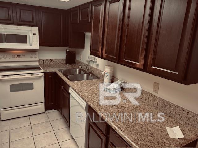 kitchen with light stone counters, white appliances, sink, and light tile patterned floors