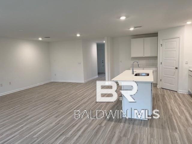32062 Lyon Rd, Spanish Fort, AL 36527 - kitchen featuring recessed lighting, an island with sink, light wood-style flooring, light countertops, and white cabinetry