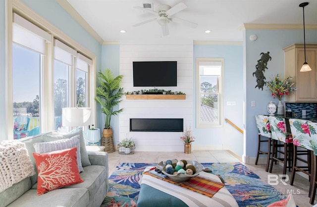 living room with visible vents, a large fireplace, ornamental molding, tile patterned floors, and a ceiling fan