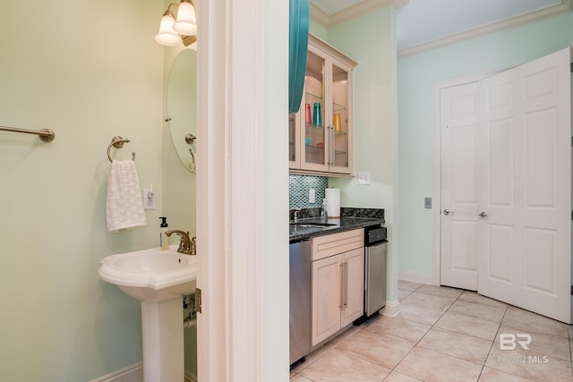 bathroom featuring tasteful backsplash, baseboards, ornamental molding, tile patterned floors, and a sink