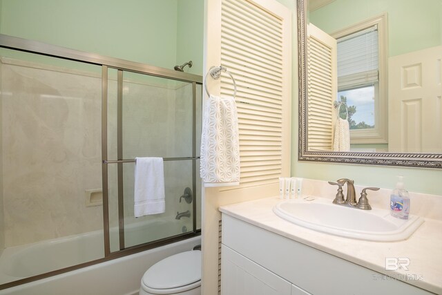 bathroom with combined bath / shower with glass door, toilet, and vanity