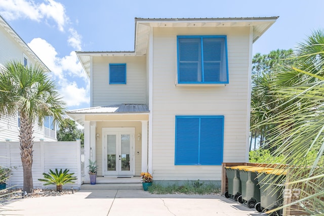 contemporary house featuring a standing seam roof, french doors, fence, and metal roof