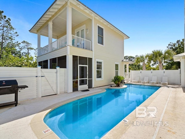 rear view of property featuring a fenced in pool, a balcony, a fenced backyard, a patio area, and a gate