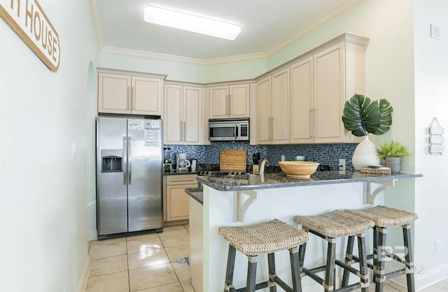 kitchen with cream cabinets, backsplash, appliances with stainless steel finishes, and ornamental molding