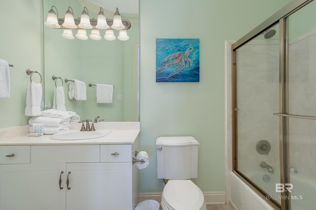 bathroom featuring vanity, toilet, baseboards, and combined bath / shower with glass door