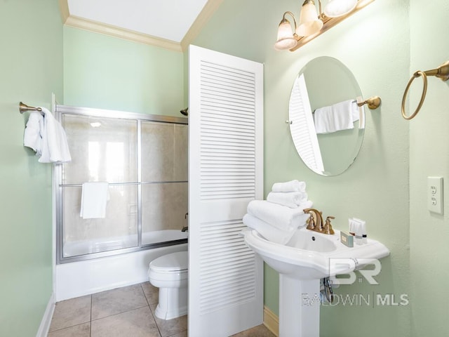 bathroom featuring toilet, ornamental molding, shower / bath combination with glass door, tile patterned flooring, and baseboards