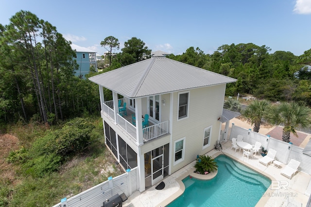 rear view of property featuring a patio, a balcony, central AC unit, a fenced backyard, and an outdoor pool