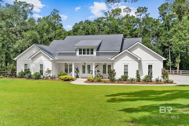 modern farmhouse featuring a front yard, a standing seam roof, roof with shingles, and fence