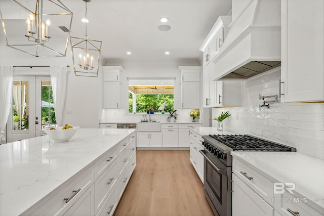 kitchen with custom exhaust hood, tasteful backsplash, high end stainless steel range oven, white cabinets, and light wood-type flooring