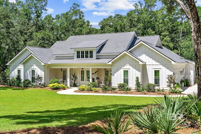 modern farmhouse with board and batten siding, a front yard, a standing seam roof, and a shingled roof