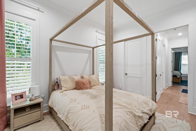 bedroom with ornamental molding and light wood-type flooring