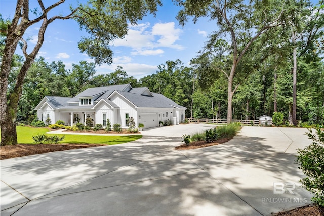 modern farmhouse style home with board and batten siding, fence, a garage, driveway, and a front lawn