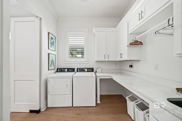 laundry area featuring ornamental molding, cabinet space, washing machine and dryer, and light wood-style flooring