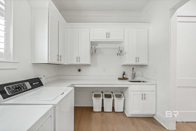 clothes washing area with light wood-type flooring, cabinet space, washer and clothes dryer, and a sink