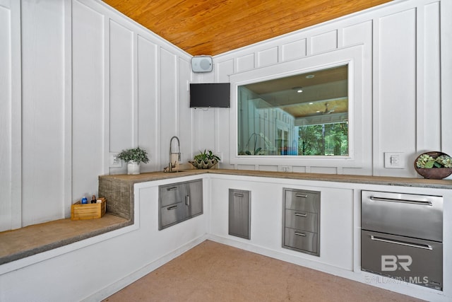 interior space featuring wooden ceiling, a decorative wall, and a sink