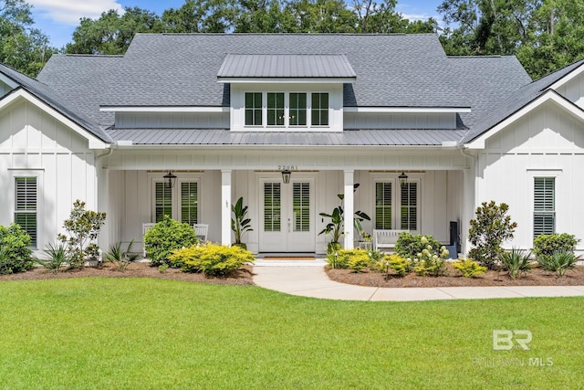 modern farmhouse style home featuring board and batten siding, a front yard, metal roof, and a porch