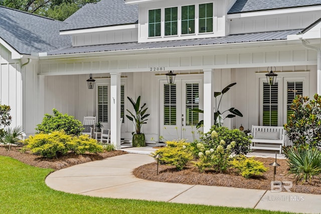 property entrance with a porch, roof with shingles, metal roof, and board and batten siding