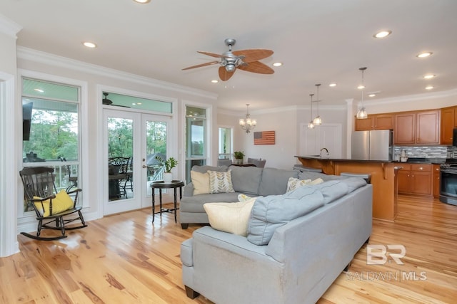 living room featuring light wood-type flooring, ceiling fan with notable chandelier, and crown molding