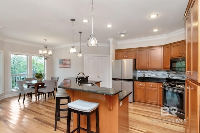 kitchen with black appliances, a center island with sink, sink, a kitchen breakfast bar, and light hardwood / wood-style floors