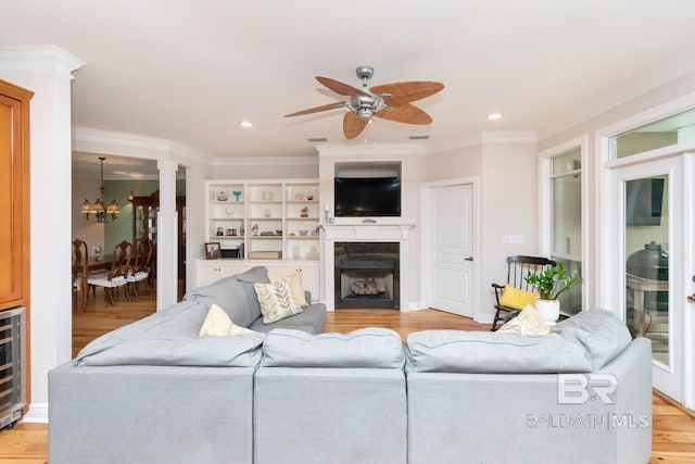 living room featuring light hardwood / wood-style floors, ceiling fan with notable chandelier, and crown molding