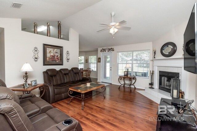 living room featuring ceiling fan, vaulted ceiling, wood-type flooring, and a fireplace