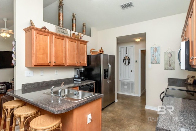 kitchen featuring dark tile patterned floors, sink, kitchen peninsula, ceiling fan, and a breakfast bar