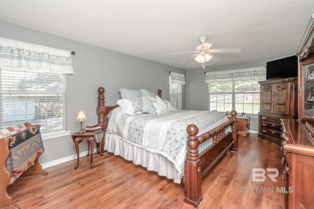 bedroom featuring hardwood / wood-style flooring, multiple windows, and ceiling fan