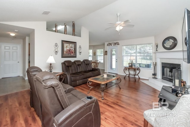 tiled living room with ceiling fan, lofted ceiling, and a tile fireplace