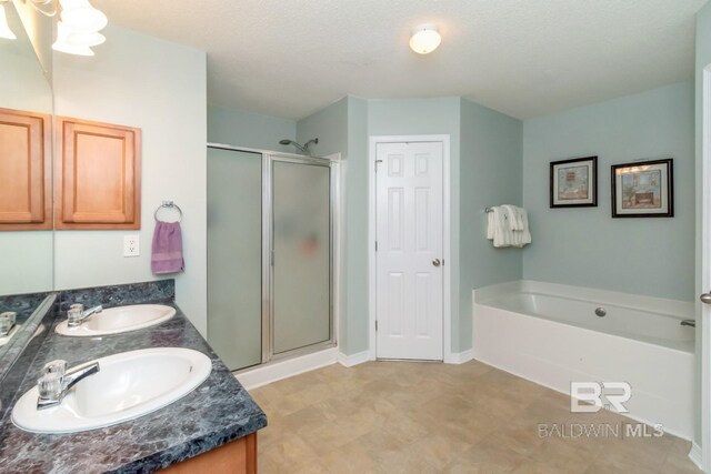 bathroom with a textured ceiling, independent shower and bath, vanity, and tile patterned floors