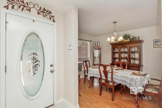 dining space with a notable chandelier, a textured ceiling, and light hardwood / wood-style floors