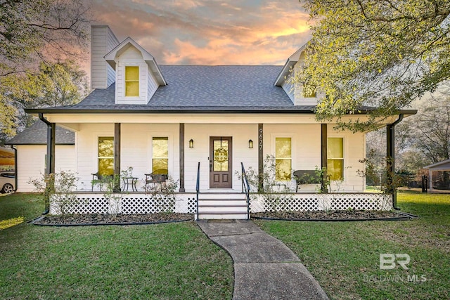 view of front of home with a porch, roof with shingles, and a front lawn