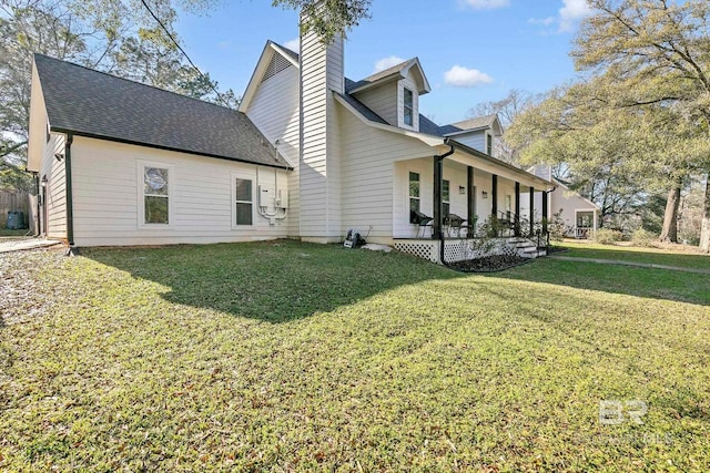 rear view of house featuring a yard, a porch, and roof with shingles