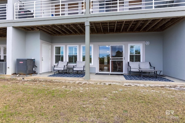 view of exterior entry featuring a patio, cooling unit, a yard, and stucco siding