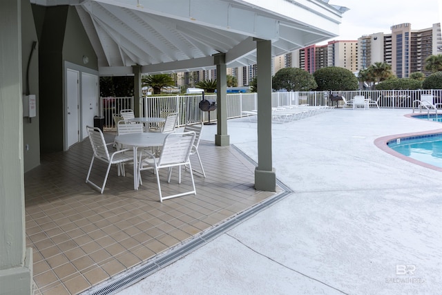 view of patio / terrace with a gazebo, a community pool, outdoor dining space, and fence