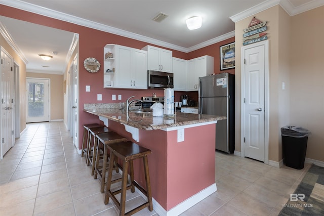 kitchen featuring stainless steel appliances, a peninsula, ornamental molding, and a breakfast bar