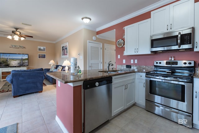 kitchen with appliances with stainless steel finishes, a peninsula, light tile patterned flooring, a ceiling fan, and a sink