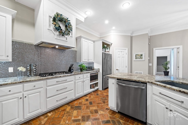 kitchen with custom exhaust hood, stainless steel appliances, ornamental molding, white cabinets, and backsplash