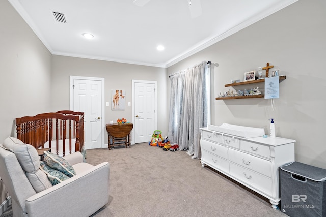 bedroom featuring a nursery area, ceiling fan, crown molding, and carpet