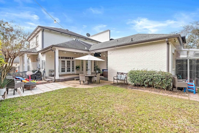 rear view of house featuring a lawn, french doors, and a patio area