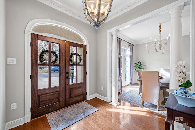 foyer entrance with a notable chandelier, french doors, wood-type flooring, and ornate columns