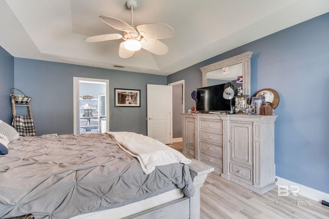 10675 Aloe Ln, Lillian, AL 36549 - bedroom featuring light wood-style flooring, a tray ceiling, baseboards, and ceiling fan