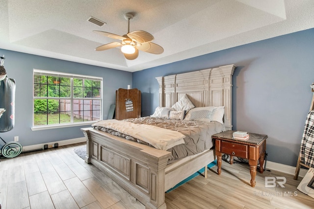 10675 Aloe Ln, Lillian, AL 36549 - bedroom with a tray ceiling, baseboards, light wood finished floors, a textured ceiling, and ceiling fan