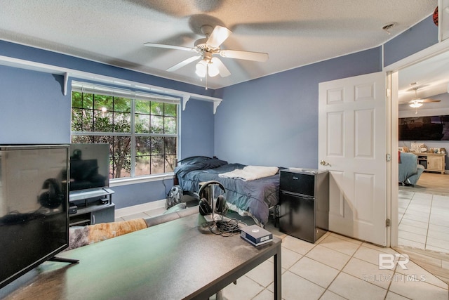 10675 Aloe Ln, Lillian, AL 36549 - bedroom with light tile patterned floors, a textured ceiling, a ceiling fan, freestanding refrigerator, and baseboards