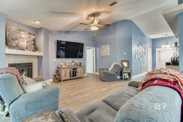 10675 Aloe Ln, Lillian, AL 36549 - living room with vaulted ceiling, ceiling fan, wood finished floors, a tiled fireplace, and baseboards