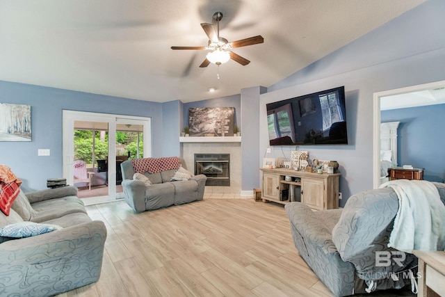 10675 Aloe Ln, Lillian, AL 36549 - living room featuring a ceiling fan, a tiled fireplace, light wood finished floors, and vaulted ceiling