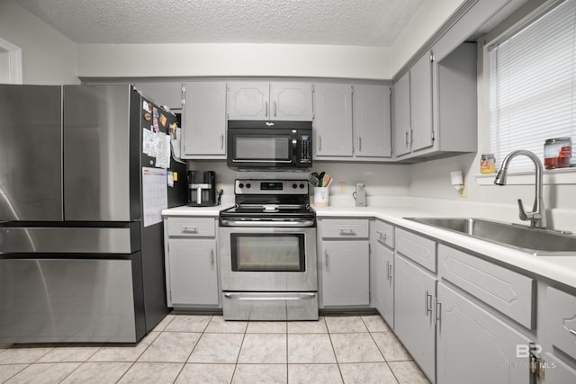 kitchen with stainless steel appliances, sink, light tile patterned floors, and gray cabinets