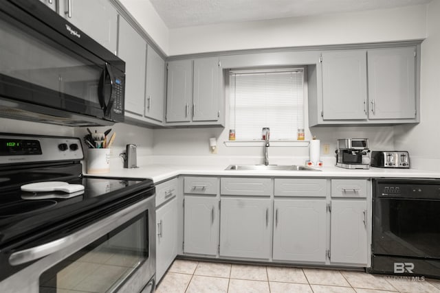 kitchen with sink, gray cabinetry, light tile patterned floors, and black appliances