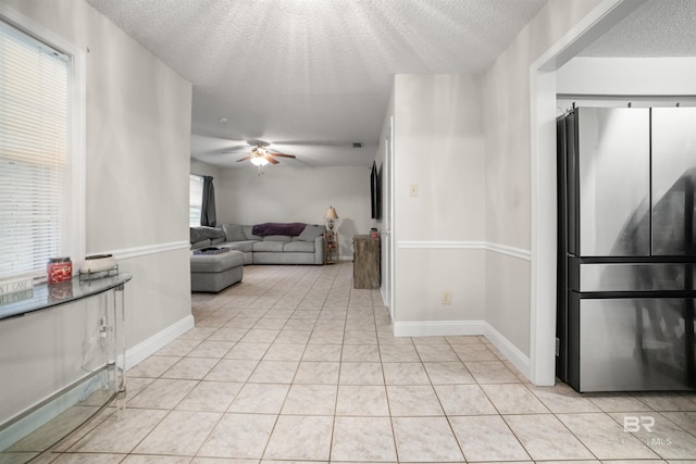 living room featuring ceiling fan, a textured ceiling, and light tile patterned floors